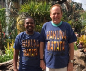 Lawrence and Gary in the African Village at Disney World wearing their matching shirts that say “no worry be happy” in Swahili.