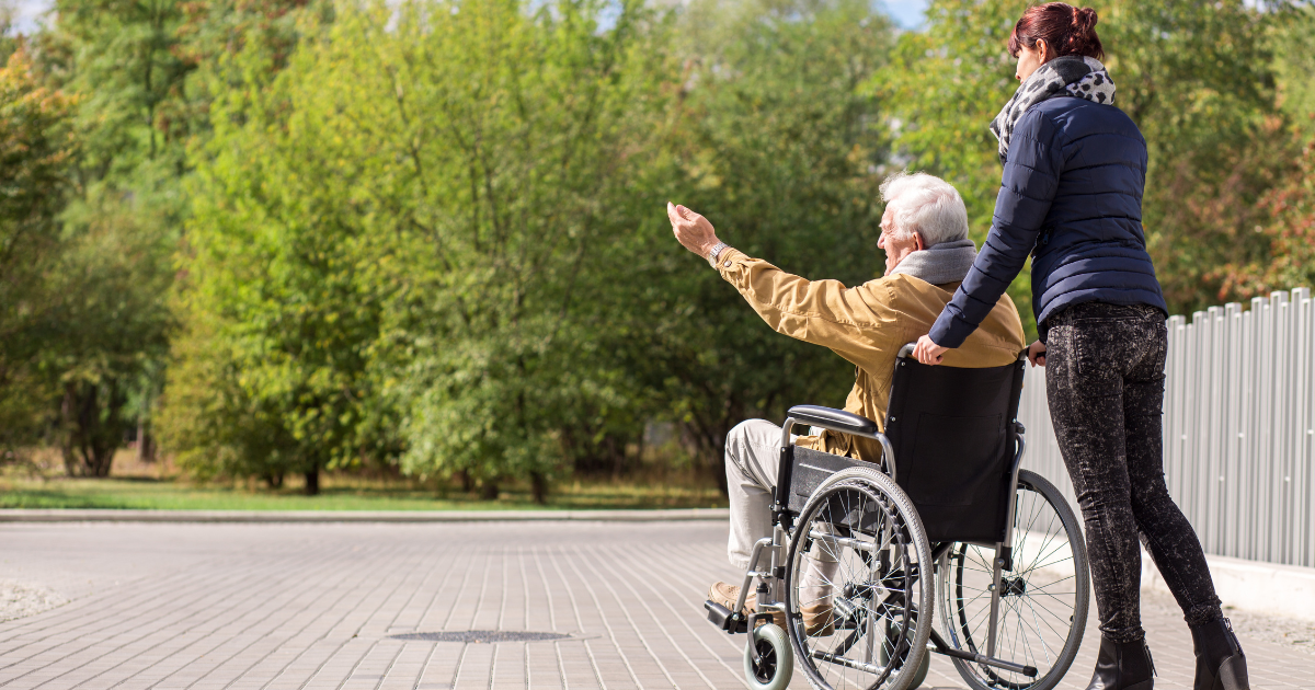 caregiver pushing client in wheelchair outside
